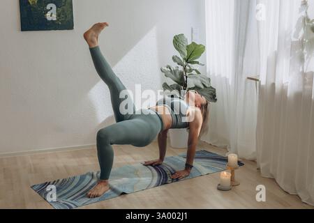 Une femme de 50 ans fait du yoga à la maison Banque D'Images