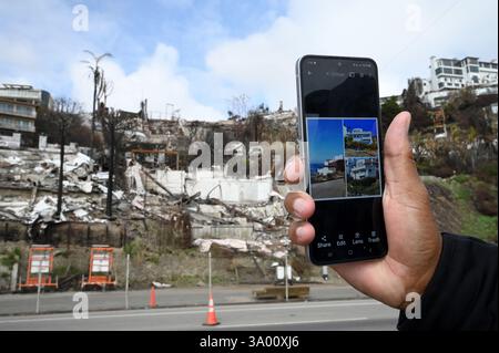 Los Angeles, États-Unis. 01 mars 2025. Un propriétaire (nom caché sur demande) tient son téléphone portable avec des photos de sa maison devant sa propriété endommagée le long de la Pacific Coast Highway près de l'incendie de Palisades dans le quartier Pacific Palisades de Los Angeles, CA, le 1er mars 2025. (Photo par Anthony Behar/SipaUSA) crédit : Sipa USA/Alamy Live News Banque D'Images