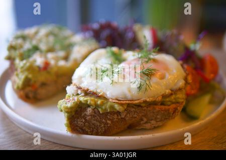 Délicieux petit déjeuner avec pain grillé à l'avocat et oeuf frit sur une assiette Banque D'Images