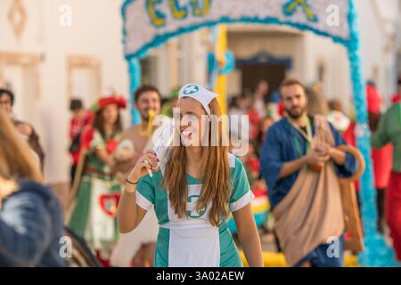 Altura, Portugal, 1er mars 2025. Les participants au carnaval habillés comme des infirmières et des médecins marchent bras dans bras, souriant et célébrant lors d'un défilé animé. Banque D'Images