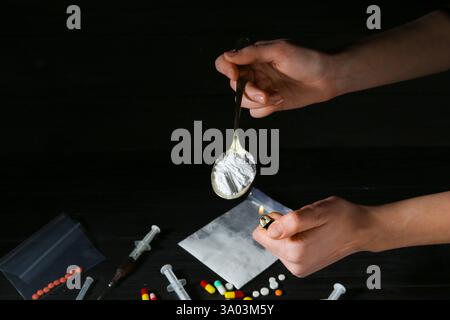 Toxicomanie. Cuillère d'éclairage de femme avec de la poudre sur fond sombre, gros plan Banque D'Images