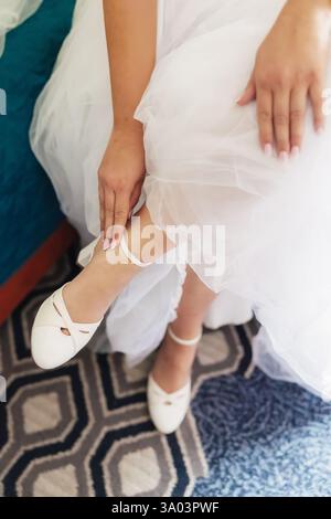 Mariée mettant sur chaussures de mariage à talons légers Banque D'Images