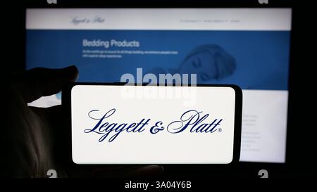 Stuttgart, Allemagne - 11-28-2024: Personne tenant un téléphone portable avec le logo de la société de fabrication américaine Leggett et Platt Inc sur l'écran en face de la page Web. Concentrez-vous sur l'affichage du téléphone. Banque D'Images