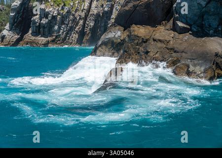 Vue rapprochée sur les eaux turquoises profondes de l'océan Atlantique s'écrasant sur les formations rocheuses déchiquetées de l'île Ilha do Farol sous une journée ensoleillée d'été après-midi. Banque D'Images