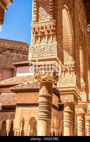 Arches nasrides soigneusement sculptées et piliers cannelés minces dans la Cour des Lions à l'Alhambra présentant Muqarnas Capitals et la calligraphie arabe Banque D'Images