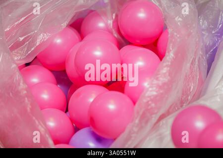 Des boules en plastique rose éclatantes débordent d'un sac en plastique transparent, créant une scène ludique et colorée Banque D'Images