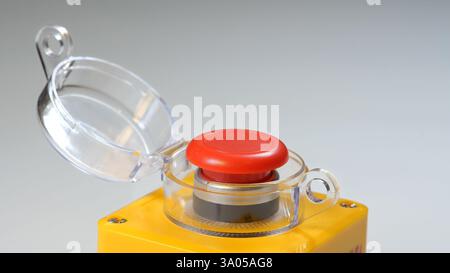 Bouton d'arrêt d'urgence industriel rouge avec couvercle de sécurité transparent ouvert, monté sur le boîtier de commande jaune pour l'arrêt de la machine, interrupteur de sécurité pour l'usine Banque D'Images