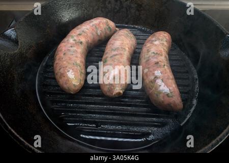 Faites cuire des saucisses de porc dans une poêle en fonte pour une saveur délicieuse. Admirez la vue aérienne de votre plat ! Banque D'Images