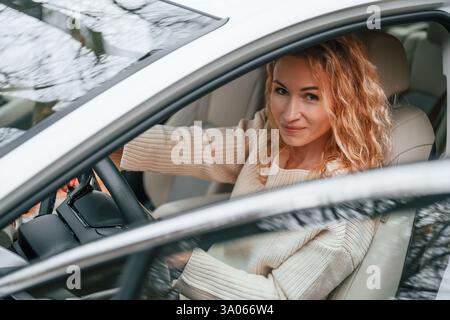 Avec la porte ouverte. La jeune femme est assise dans l'automobile. Banque D'Images
