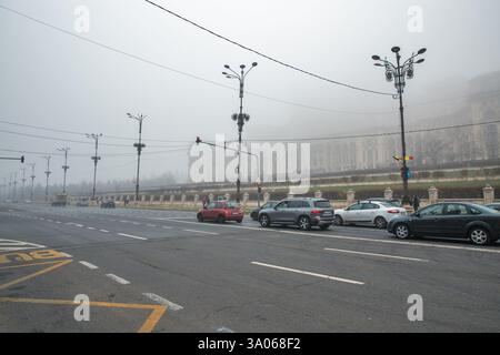 Bucarest, Roumanie - 31 décembre 2024 : Boulevard de la liberté et Palais du Parlement pendant un épais brouillard en hiver. Banque D'Images