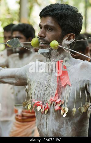 Homme perçant la pointe à travers les joues déchargeant le vœu au festival de Thaipusam, Kerala, Inde NOMR Banque D'Images