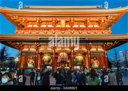 Les visiteurs se tiennent devant la porte Kamenari-mon, qui marque l'une des entrées du temple Senso-ji à Tokyo, au Japon Banque D'Images