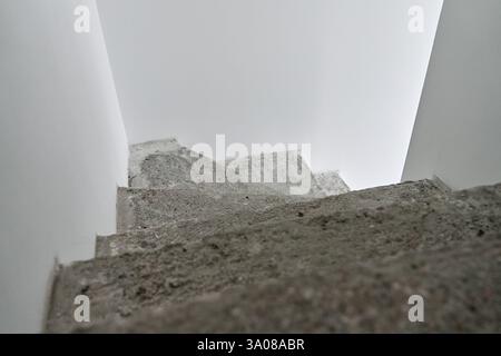 Escalier en béton non fini dans un intérieur minimaliste moderne. Appartement neuf avec des éléments de construction bruts et des murs blancs. Bâtiment en réparation Banque D'Images