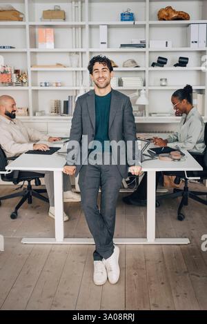 Portrait de jeune homme d'affaires souriant debout près du bureau au bureau créatif Banque D'Images