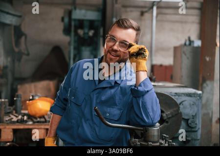 Ouvrier d'usine en uniforme bleu est à l'intérieur. Banque D'Images