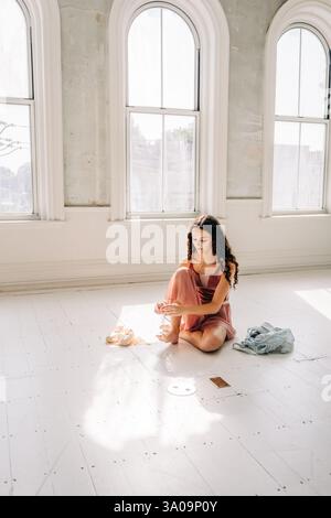 Ballerine est assise sur le sol, préparant ses pieds pour les chaussures pointe Banque D'Images