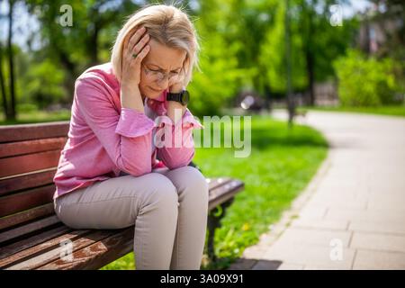 Portrait de femme mature dans le parc. Elle est déprimée. Banque D'Images