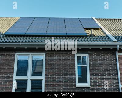 Une maison moderne à Assen, aux pays-Bas, avec des panneaux solaires sur le toit en tuiles, avec une façade en briques, de grandes fenêtres et des solutions énergétiques durables. Banque D'Images
