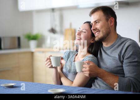 Heureux couple interracial buvant du café contemplant dans la cuisine à la maison Banque D'Images