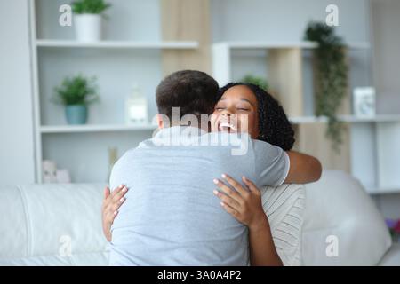 Femme noire heureuse embrassant un homme assis sur un canapé à la maison Banque D'Images