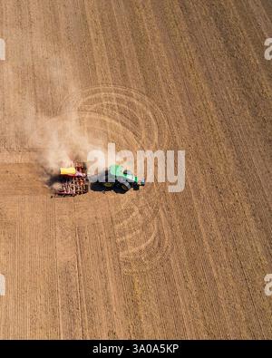 Tracteur labourant les champs agricoles, les lignes lisses du sol labouré mettent en évidence l'échelle du travail. Préparation saison de plantation, activité agricole. Aeri Banque D'Images