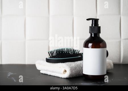 Bouteille de shampooing, serviette et brosse à cheveux dans la salle de bain. Banque D'Images