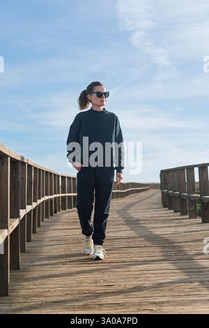 femme sportive marchant le long d'une promenade dans un survêtement Banque D'Images