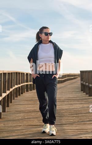 femme sportive marchant le long d'une promenade dans un survêtement Banque D'Images