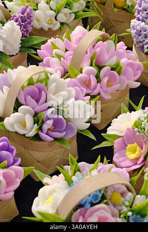 Petits bouquets de printemps faits de fleurs artificielles dans des paniers en bois d'osier, gros plan, fond abstrait Banque D'Images