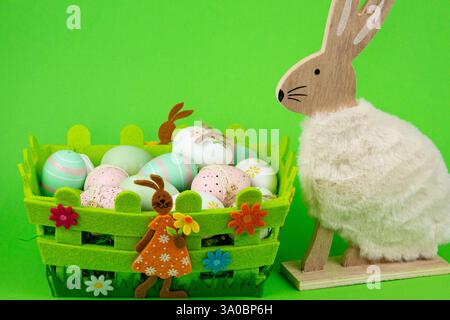 Oeufs peints de Pâques dans un panier vert sur fond vert. Composition de Pâques. Photo de haute qualité Banque D'Images