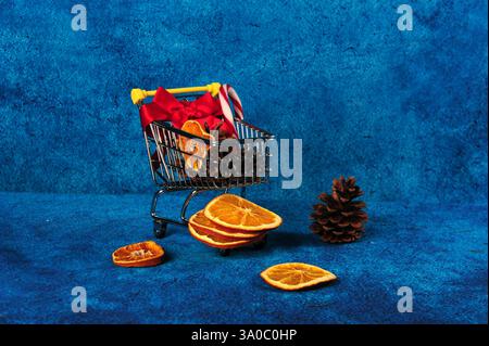Mini chariot avec contenu sur le thème de Noël. Copiez l'espace à droite sur la couleur bleue. Banque D'Images