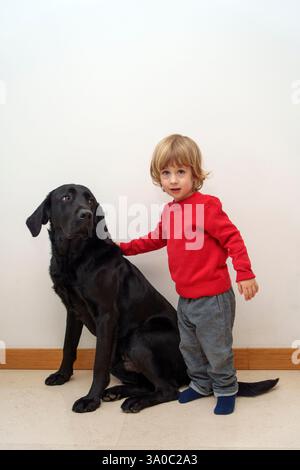 Tout-petit avec chien labrador retriever noir Banque D'Images