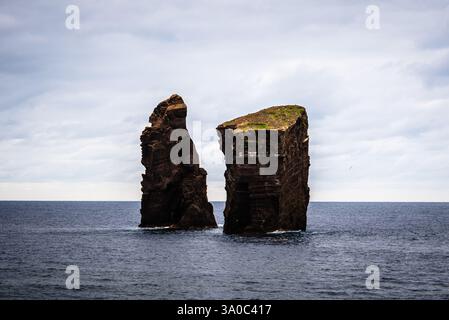 Deux îlots rocheux se dressent dans l'océan Atlantique sous un ciel nuageux, créant un paysage marin spectaculaire près de Praia dos Mosteiros, aux Açores. Banque D'Images