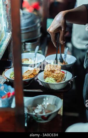 Fournisseur d'aliments de rue préparant des nouilles au poulet avec des wontons frits Banque D'Images