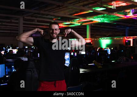 Jeune homme, joueur au festival numérique, debout dans la salle informatique et regardant la caméra. Le style de vie des jeux et les concepts communautaires. Banque D'Images