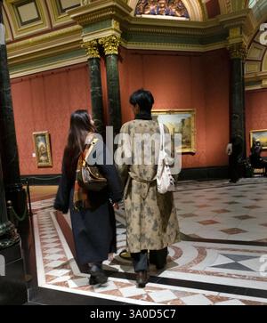Vue arrière d'un jeune couple japonais dans des vêtements à la mode manteaux d'hiver marchant à travers une salle de la National Gallery à Londres Angleterre KATHY DEWITT 2025 Banque D'Images