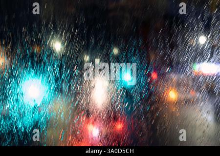 Vue sur un magasin coloré et des feux de circulation de voiture dans une rue la nuit à Londres vue à travers un bus à impériale à double étage dernier étage fenêtre de pluie Londres Royaume-Uni Banque D'Images