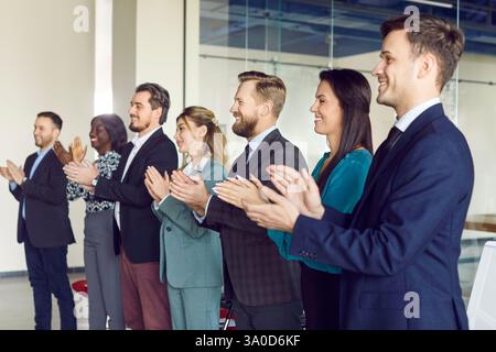 Heureux employés d'équipe positive multiethnique applaudissant dans le bureau, félicitant l'équipe, la réussite professionnelle Banque D'Images