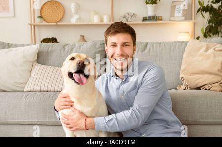 Jeune homme heureux avec chien assis sur le sol Banque D'Images