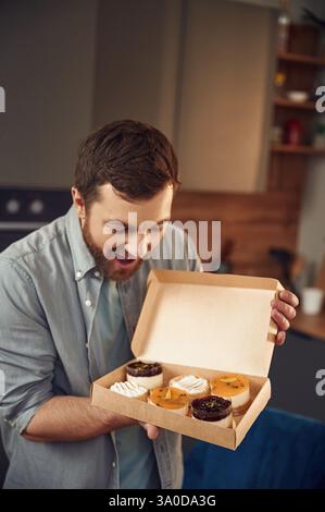 L'homme est avec de délicieux desserts qui sont dans les boîtes écologiques. Debout à l'intérieur. Banque D'Images