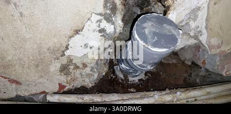 Un plombier qualifié travaille avec diligence sur l'installation d'un tuyau de plomberie dans un mur partiellement construit, assurant un alignement et un ajustement appropriés comme Dawn br Banque D'Images