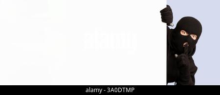 Voleur masqué qui a fait un coup de tête sur un tableau blanc, faisant un signe de hush Banque D'Images