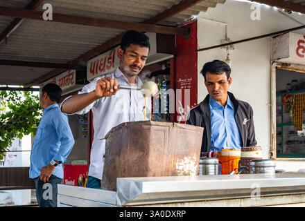 Un jeune homme qui fait du thé épicé, ou masala chai, sur un poêle. Rajasthan, Inde. Banque D'Images