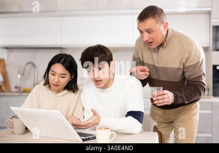 Une famille amicale regarde quelque chose ensemble sur Internet ou des chats vidéo via un ordinateur portable Banque D'Images