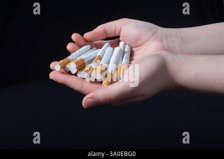 La main est de donner des paquet de cigarettes sur fond noir Banque D'Images