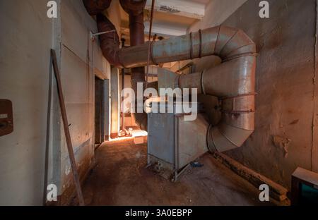 Fragment d'un système de ventilation industriel rouillé avec un filtre dans une usine abandonnée Banque D'Images