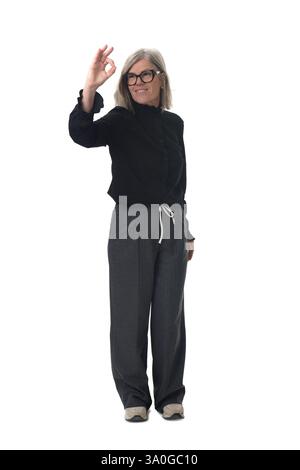 femme debout montrant et regardant le signe ok qu'elle fait avec sa main Banque D'Images