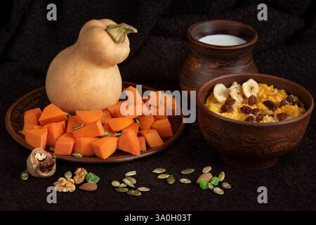 Bouillie de riz cuite dans du lait avec de la citrouille et du millet, avec du beurre, des raisins secs, de la banane et des noix. Alimentation saine à partir de produits naturels. Banque D'Images