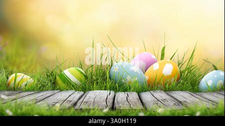 Six œufs de pâques peints célébrant une joyeuse Pâques un jour de printemps avec une prairie d'herbe verte, la lumière du soleil et un fond coloré. Banque D'Images