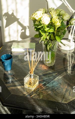 Diffuseur de roses blanches et de roseaux sur une table en bois Banque D'Images